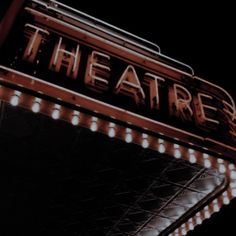 the theatre sign lit up at night with lights on it's sides and below