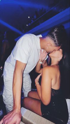 a man kissing a woman on the cheek in front of a crowd at a party