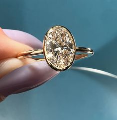 a close up of a person's hand holding a ring with a diamond in it