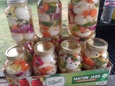 mason jars filled with pickled vegetables sitting on top of a table next to a cardboard box