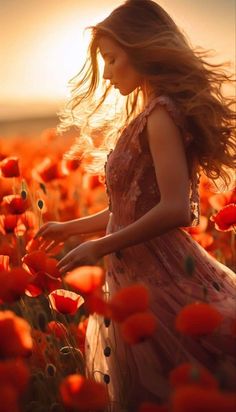 a woman standing in a field of red flowers with her hair blowing in the wind