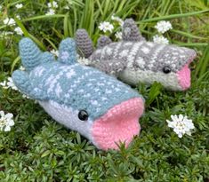 two crocheted stuffed animals laying on top of some green grass and white flowers