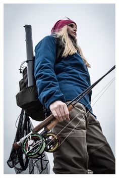 a woman holding onto a fishing pole while standing next to a net