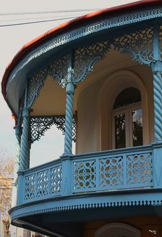 an ornate blue building with red roof and balcony