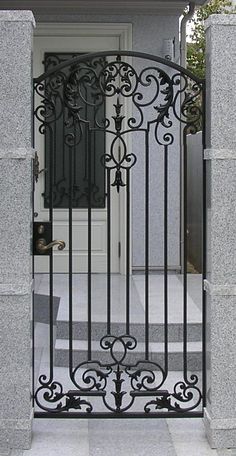 an iron gate is open on the outside of a house in front of a door