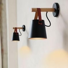 two lamps are hanging on the wall next to each other, one is black and one is brown