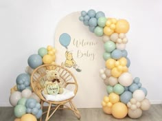 the balloon arch is decorated with winnie the pooh balloons and a teddy bear sitting on a chair