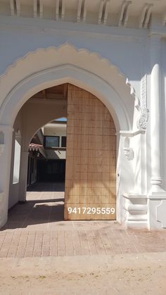 an archway leading to a white building with a wooden door on the front and side