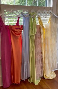 four dresses hanging on a rack in front of a window