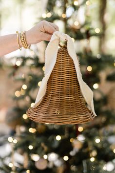 a person holding a basket in front of a christmas tree