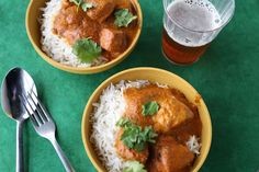 two bowls filled with rice, meat and cilantro on top of a green table