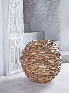 a basket sitting on top of a wooden floor next to a white wall and stairs