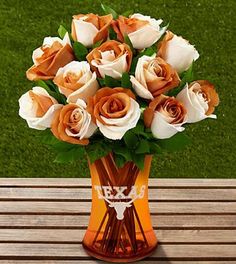 a vase filled with orange and white flowers sitting on top of a wooden bench next to a field