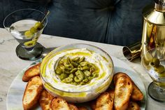 an appetizer with olives and cream cheese on a plate next to two glasses