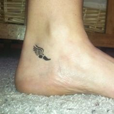 a small tattoo on the foot of a woman's left foot, with an angel wing