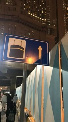 there is a blue street sign with an arrow pointing to the right and people walking by