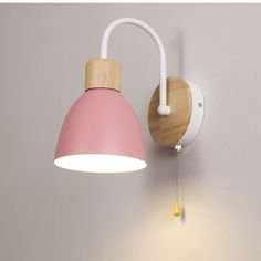 a pink and white wall light on a gray wall with a wooden handle attached to it