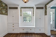 an empty room with white cupboards and drawers on the wall next to a window