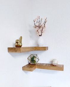 two wooden shelves with vases and other decorative items on them against a white wall