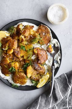 a black plate topped with potatoes and meat