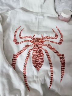 a white shirt with red spider drawn on it