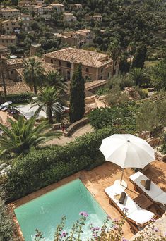 an outdoor swimming pool with lounge chairs and umbrellas next to it, surrounded by greenery