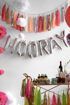 balloons and streamers are hanging from the ceiling above a table filled with food, drinks and decorations