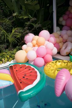 an inflatable watermelon float sitting on top of a pool surrounded by balloons