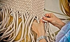 two women are working on a large piece of art that looks like woven material with fringes