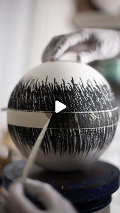 someone is painting an egg with black and white paint