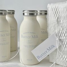 three white jars with labels on them sitting next to a basket and some paper towels