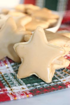 some cookies with icing are on a plaid table cloth and one is shaped like a star