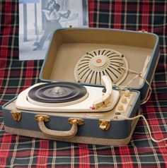 a suitcase with a record player in it on a plaid cloth tablecloth next to an album