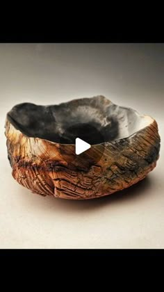 a wooden bowl sitting on top of a white table next to a black object in the middle