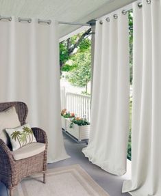 a chair sitting on top of a rug next to a window covered in white curtains