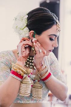 a woman wearing jewelry and holding her hands to her face