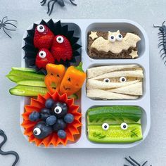 a tray filled with different types of food on top of a white table next to halloween decorations