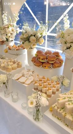 an assortment of desserts and pastries on a table with flowers in vases