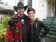 two men standing next to each other in front of a house