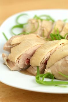 a white plate topped with sliced up meat and veggies on top of a wooden table