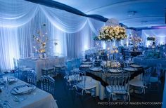 a banquet room with white table cloths and tall centerpieces