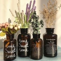 three brown vases with flowers in them sitting on a table next to each other