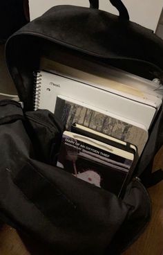 a black backpack filled with books on top of a wooden table