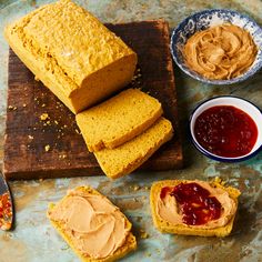 peanut butter and jelly bread on a cutting board with two bowls of jams next to it