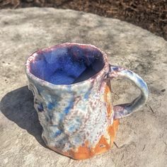 a ceramic mug sitting on top of a rock