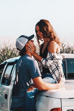 two people are sitting on the back of a pickup truck and one person is hugging her