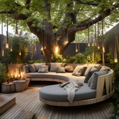 a circular couch sitting on top of a wooden floor next to a tree with candles