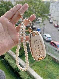 a hand holding a car key chain with a cell phone attached to it