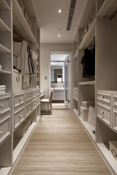 an empty walk - in closet with white drawers and wooden flooring is seen here