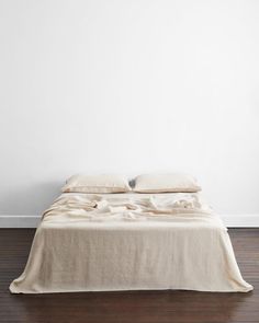 an unmade bed in a white room with wood flooring and wall paint on the walls